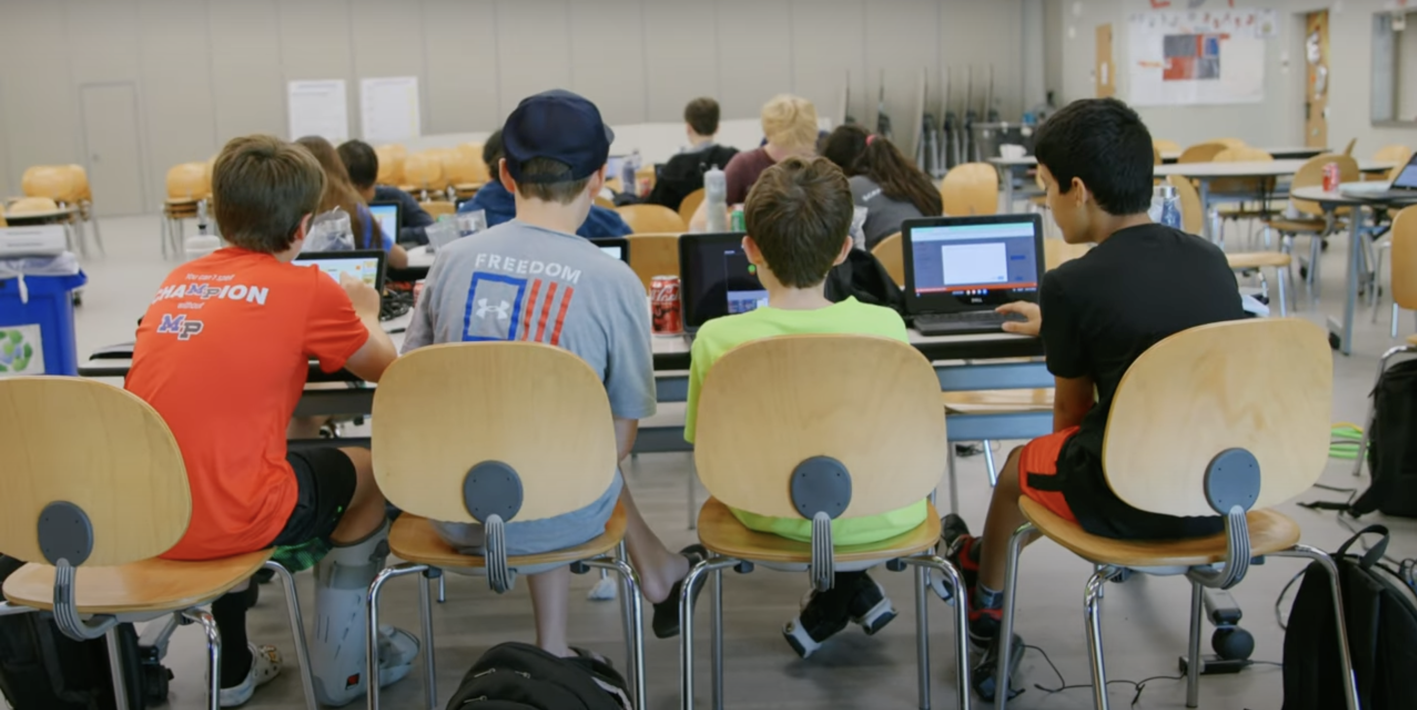 A row of k12 school GCISD kids gathered around a table during Lightspeed's Beat the Filter ethical hackithon